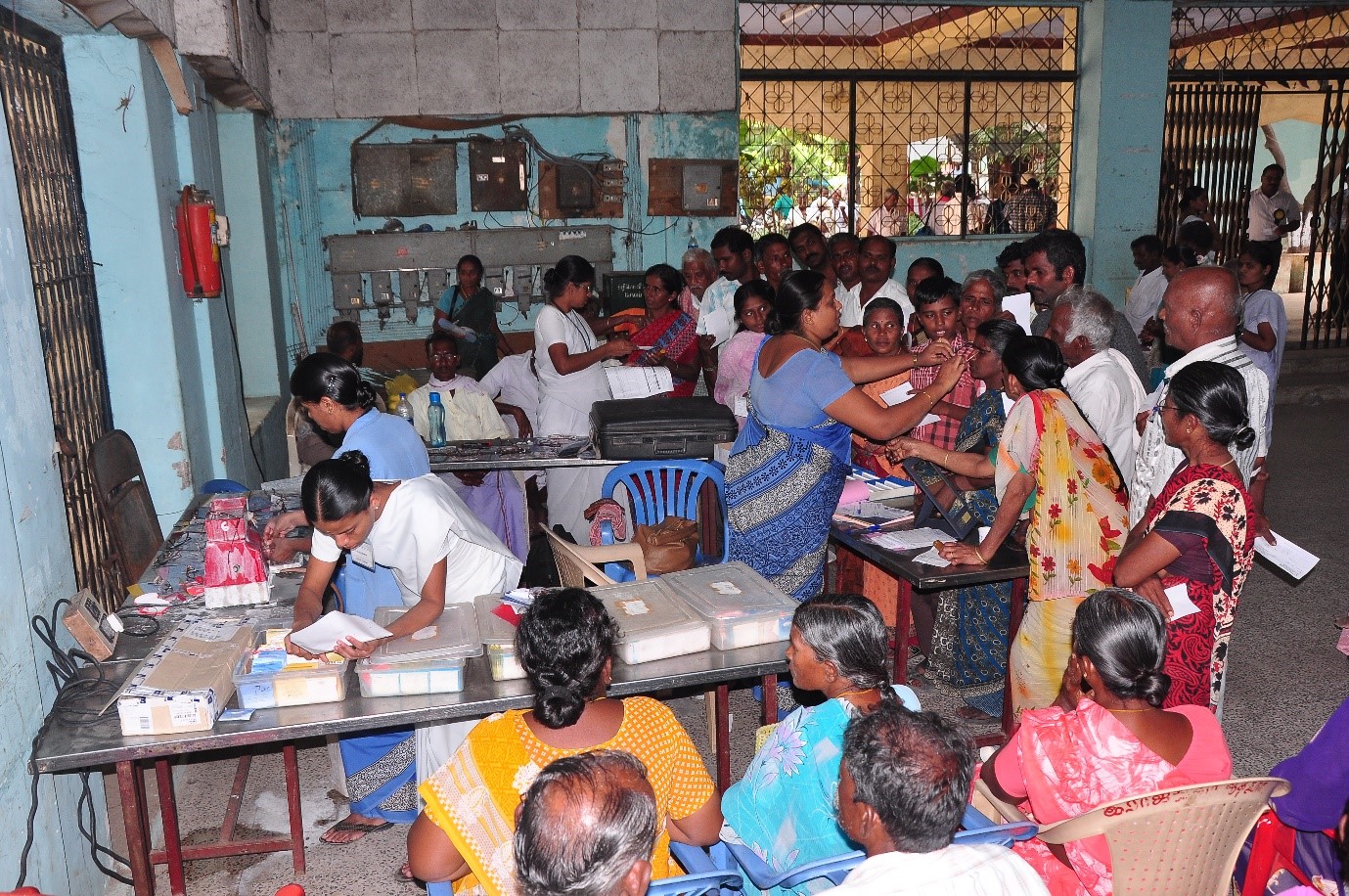 Spectacle dispensing at a rural Aravind eye camp. An optician helps patients choose from a selection of frames while technicians select the prescribed lenses, edge and fit them. INDIA (c)ARAVIND EYE CARE SYSTEMS