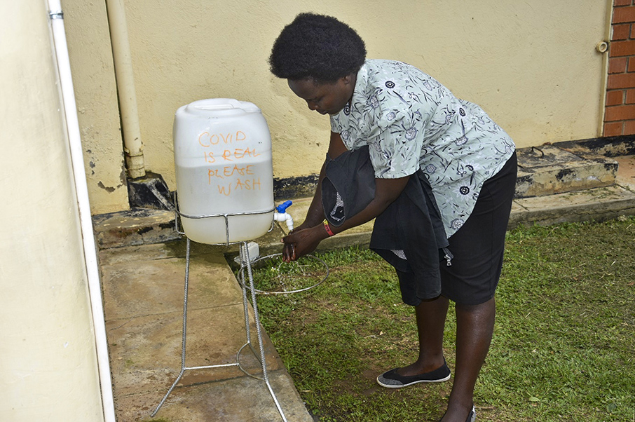 A patient washes hands before accessing the clinic building at MURHEC.