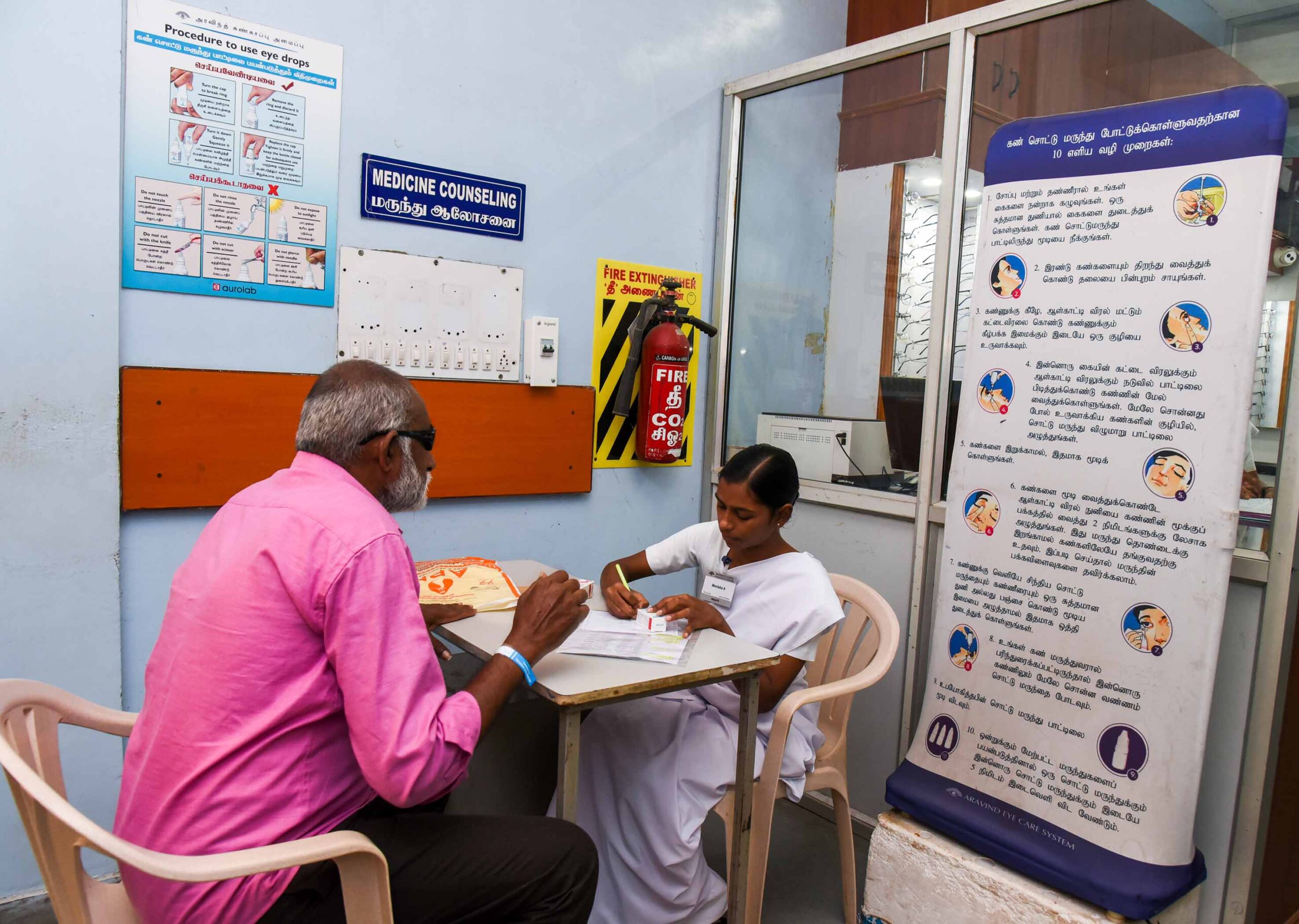 A pharmacy assistant counsels a patient about his eye medicines and how to use them. INDIA